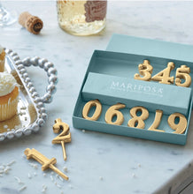 Load image into Gallery viewer, Mariposa gold number candle holders displayed in gift box alongside celebratory cupcakes and champagne
