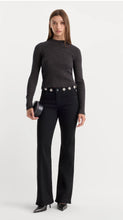 Load image into Gallery viewer, Model wearing high-waist flared jeans with floral daisy embellishments along the waistband