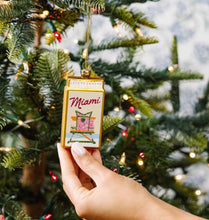 Load image into Gallery viewer, Hand holding a decorative Miami-themed matchbox Christmas tree ornament with lifeguard stand