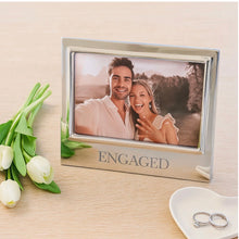 Load image into Gallery viewer, Mariposa Engaged Signature Frame displayed with a couple's engagement photo, tulips, and rings nearby.