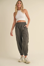 Load image into Gallery viewer, Woman wearing relaxed-fit cargo jogger pants with elastic waistband and side pockets