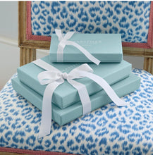 Load image into Gallery viewer, Mariposa gift boxes with white ribbon bows stacked on a patterned chair
