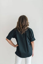 Load image into Gallery viewer, Black short sleeve ruffle cuff shirt, back view, paired with white pants.