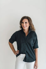 Load image into Gallery viewer, Black short-sleeve button-front shirt with ruffle collar, worn with white jeans.