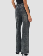 Load image into Gallery viewer, Woman wearing wide-leg denim track pants with elastic waistband, paired with heels, back view
