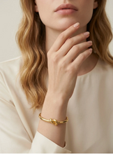 Load image into Gallery viewer, Model wearing Tat2 Noa Knot Bangle, a sleek gold bangle with an elegant knot detail