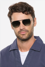 Load image into Gallery viewer, Man with curly hair wearing sleek aviator sunglasses with thin metal frames and gradient lenses