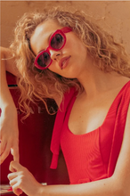 Load image into Gallery viewer, Woman with curly hair wearing bold oval cat-eye sunglasses, posing confidently outdoors