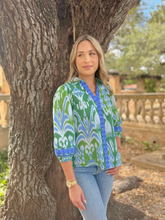 Load image into Gallery viewer, Woman wearing a printed boho-style button-front blouse with decorative trim details, paired with jeans