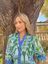 Load image into Gallery viewer, Woman wearing a printed button-down blouse with ikat pattern and rolled sleeves outdoors