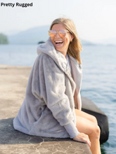 Load image into Gallery viewer, Woman laughing outdoors wearing a cozy hooded faux fur Pretty Rugged cardigan by a lake