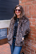 Load image into Gallery viewer, Woman wearing a luxurious leopard print faux fur capelet coat leaning against brick wall