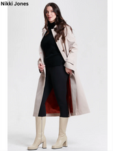 Load image into Gallery viewer, Woman wearing a classic belted trench coat with red lining, styled over black outfit