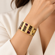 Load image into Gallery viewer, Brackish Cora Striped Hinge Cuff bracelet featuring gold metal and feather inlay panels worn on wrist