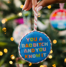 Load image into Gallery viewer, Needlepoint Christmas ornament with bold embroidered text hung on a holiday tree