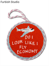 Load image into Gallery viewer, Round needlepoint ornament featuring an airplane and humorous 'Do I Look Like I Fly Economy' text