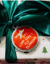 Load image into Gallery viewer, Needlepoint Christmas ornament with airplane graphic reading 'Do I Look Like I Fly Economy'