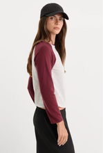 Load image into Gallery viewer, Woman wearing a long sleeve raglan crop tee with baseball cap, side view