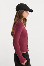 Load image into Gallery viewer, Woman wearing a fitted ribbed V-neck button-front cardigan with long sleeves and baseball cap
