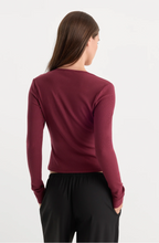 Load image into Gallery viewer, Woman wearing a fitted ribbed long sleeve V-neck cardigan, shown from behind