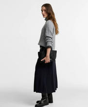 Load image into Gallery viewer, Woman wearing a cable-knit turtleneck sweater paired with a pleated midi skirt and boots