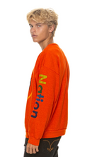 Load image into Gallery viewer, Male model wearing a relaxed fit crewneck sweatshirt with multicolor sleeve graphic lettering