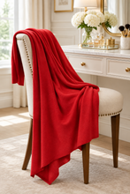 Load image into Gallery viewer, Red cashmere travel scarf draped over ivory nailhead accent vanity chair