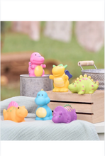Load image into Gallery viewer, Six cute dinosaur-shaped rubber squirt bath toys displayed outdoors on wooden crates