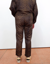 Load image into Gallery viewer, Slim-fit leopard print pants in brown and black, back view, worn with wedge sneakers