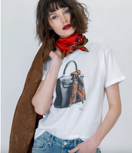 Load image into Gallery viewer, Woman wearing a graphic tee featuring a luxury handbag with scarf, styled with jeans and jacket