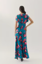 Load image into Gallery viewer, Woman wearing a floral maxi dress with flutter sleeves and flowing skirt, back view