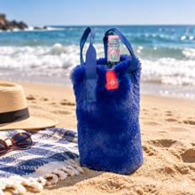 Load image into Gallery viewer, Fluffy faux fur wine tote bag with handles sitting on sandy beach with ocean backdrop