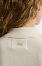 Load image into Gallery viewer, Close-up of Barbour Wynn Polo Sweater back detail showing gold logo badge and ribbed collar
