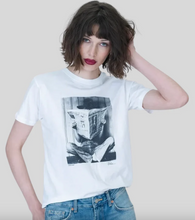 Load image into Gallery viewer, Model wearing a graphic tee featuring a vintage-style photo of someone reading a newspaper