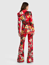 Load image into Gallery viewer, Back view of a fitted long blazer with vibrant floral print on red background with flared trousers