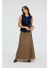 Load image into Gallery viewer, Model wearing a floor-length chevron-patterned maxi skirt paired with a navy denim vest