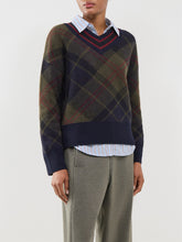 Load image into Gallery viewer, Model wearing a V-neck argyle knit sweater layered over a striped shirt with grey trousers