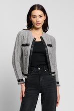 Load image into Gallery viewer, Model wearing a grey cable-knit cardigan with black leather trim and turnlock button closures
