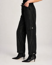 Load image into Gallery viewer, Side view of black cargo pants with snap pockets and cuffed hem on model wearing kitten heel boots