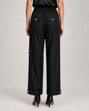 Load image into Gallery viewer, Back view of wide-leg black cargo pants with snap pockets and cuffed hem on model
