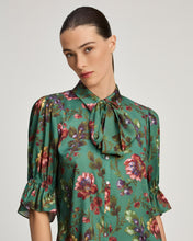 Load image into Gallery viewer, Model wearing a green floral bow-neck blouse with puffed sleeves and ruffle cuffs