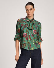 Load image into Gallery viewer, Model wearing a green floral bow-neck blouse with puffed sleeves and button front