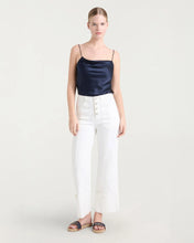 Load image into Gallery viewer, Model wearing a navy satin cowl-neck camisole with thin straps, paired with white trousers