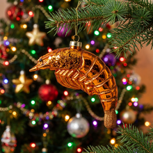Load image into Gallery viewer, Glossy glass shrimp ornament with glitter details hanging on a decorated Christmas tree