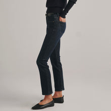 Load image into Gallery viewer, Model wearing dark indigo straight ankle jeans with black sweater and ballet flats, side view