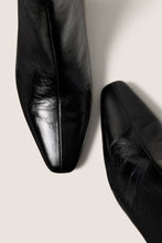 Load image into Gallery viewer, Close-up detail of two pointed-toe black leather boots showing toe box and creased texture
