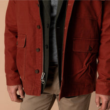 Load image into Gallery viewer, Close-up detail of a rust-brown canvas barn coat with zip closure and patch pockets