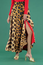 Load image into Gallery viewer, Model wearing a flowing leopard print maxi skirt with front slit and gold bow mules