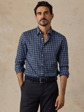 Load image into Gallery viewer, Man wearing a long-sleeve navy plaid button-up shirt with sleeves rolled, tucked into dark trousers
