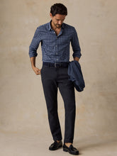 Load image into Gallery viewer, Man wearing a navy plaid button-down shirt tucked into dark trousers, holding a blazer